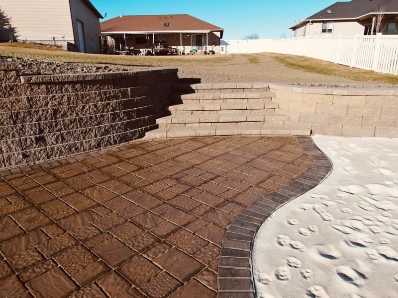 Patio de adoquines con muro de contención de bloques y escalones integrados