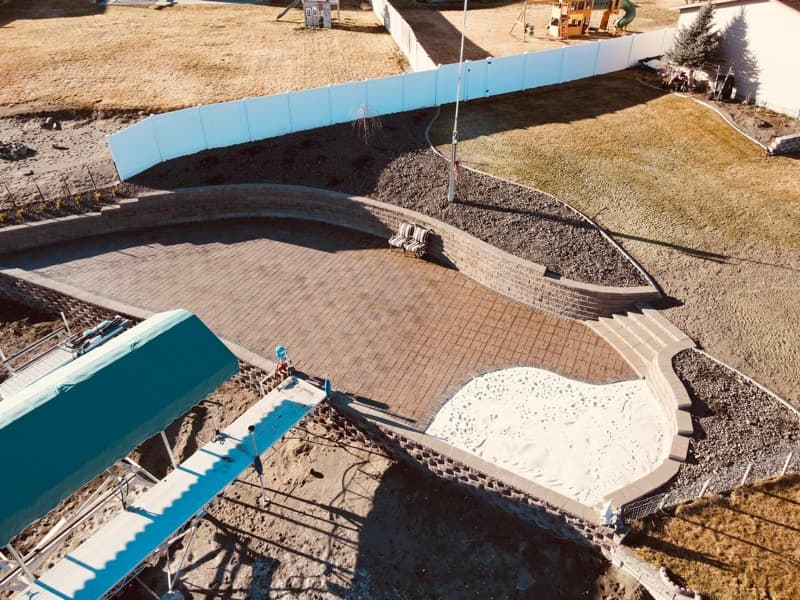Aerial view of a curved paver patio with retaining walls and steps