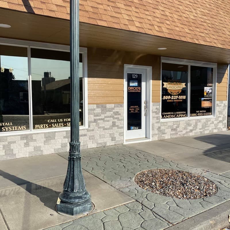 Stamped concrete sidewalk with a decorative rock planter outside a storefront