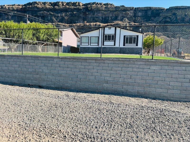 Finished block retaining wall below a fenced yard