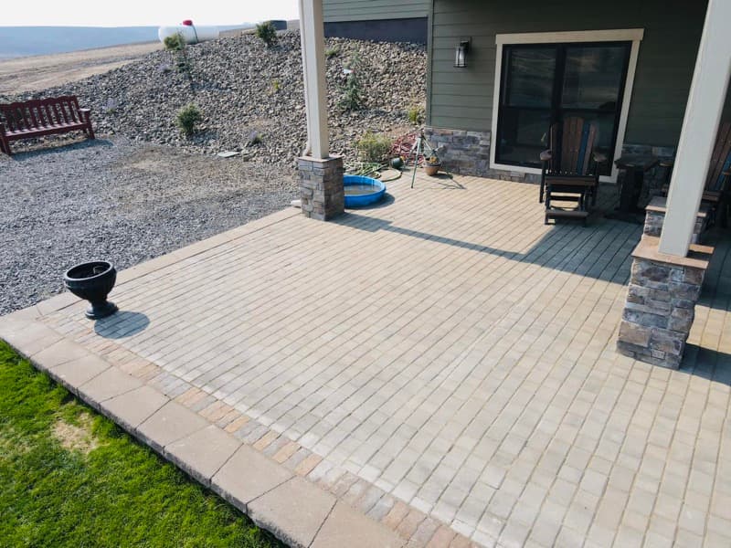 Patio de adoquines y césped detrás de una casa nueva