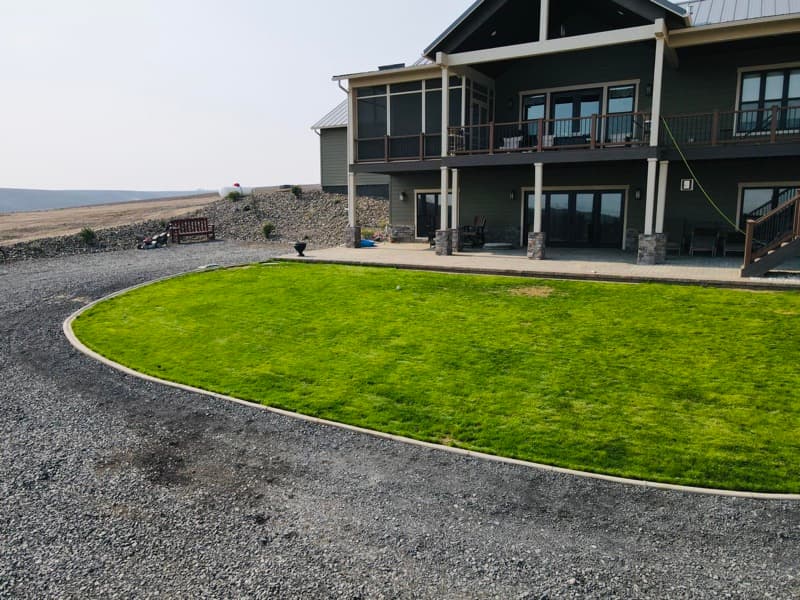 Curved lawn bordered by a gravel drive in front of a new two-story home