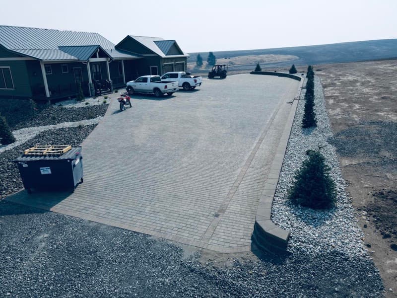 Aerial view of a paver driveway and rock landscaping at a new build