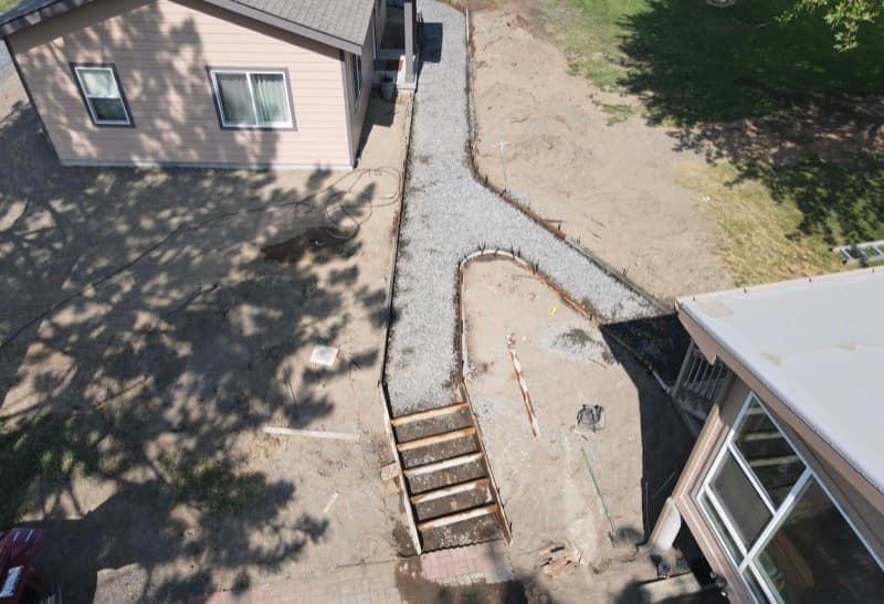 Vista aérea de un sendero de grava y escalones en construcción junto a una casa