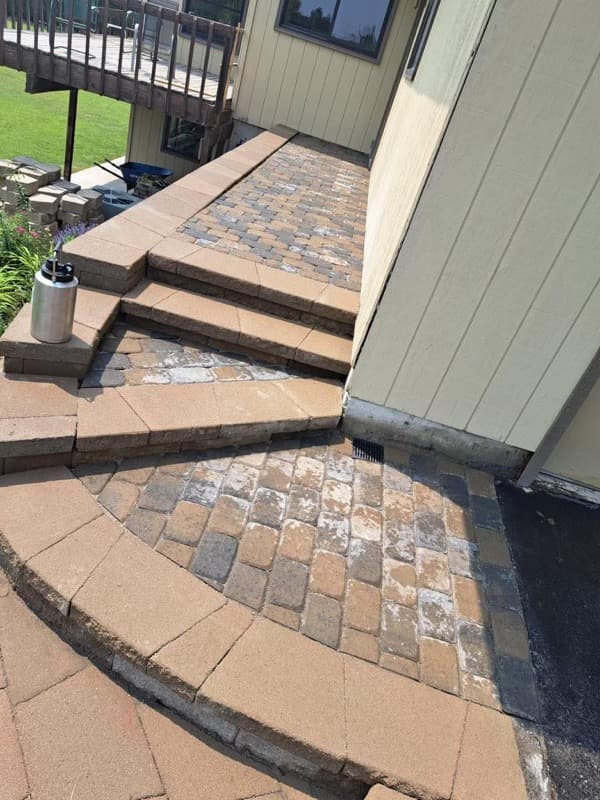Patio curvo de adoquines con escalones junto a una casa