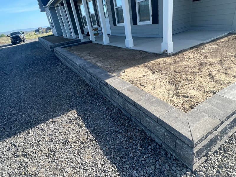 Muro de contención de bloques que bordea una jardinera frente al porche