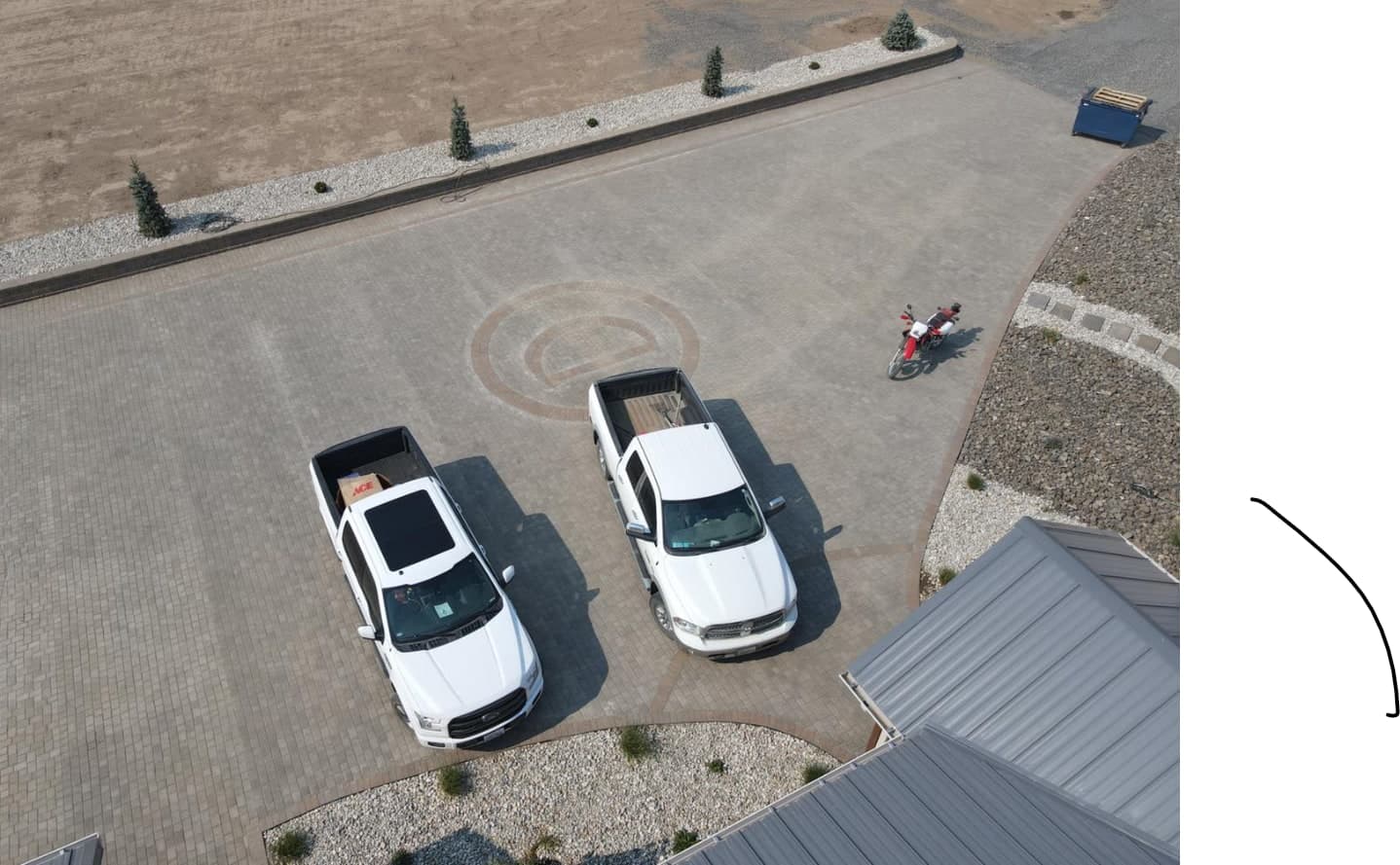 Vista aérea de una entrada de adoquines con un diseño circular y jardinería con piedra