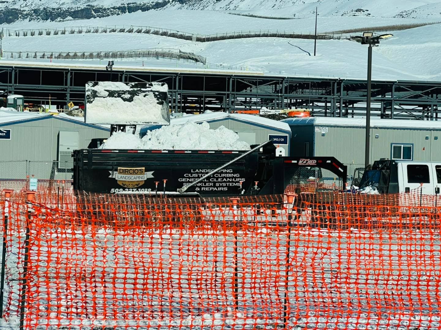 Remolque de volteo de Dircio's Landscaping llevándose nieve de un sitio comercial