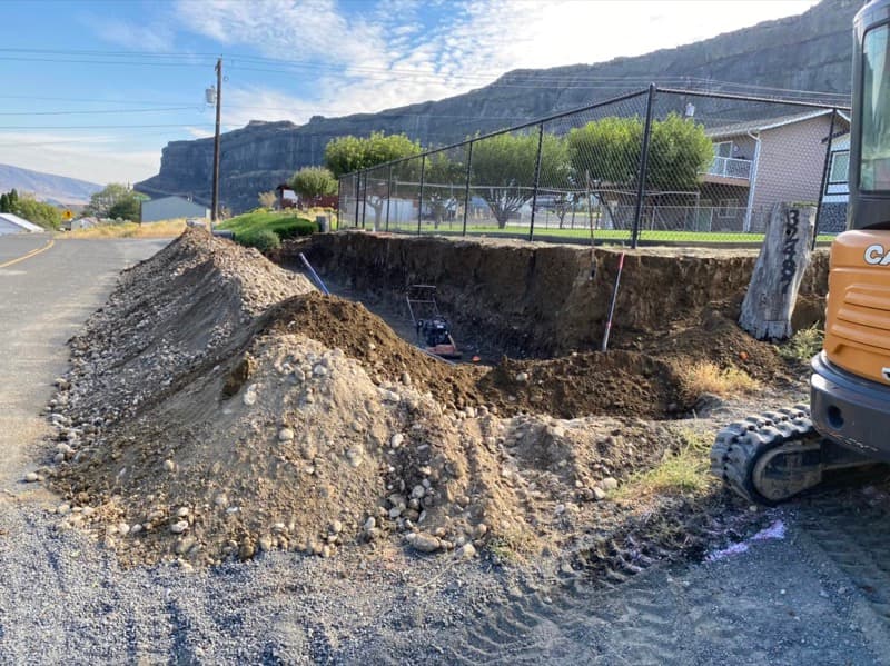 Excavator digging out a slope for a new retaining wall
