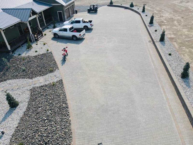 Aerial view of a paver driveway lined with rock beds and shrubs
