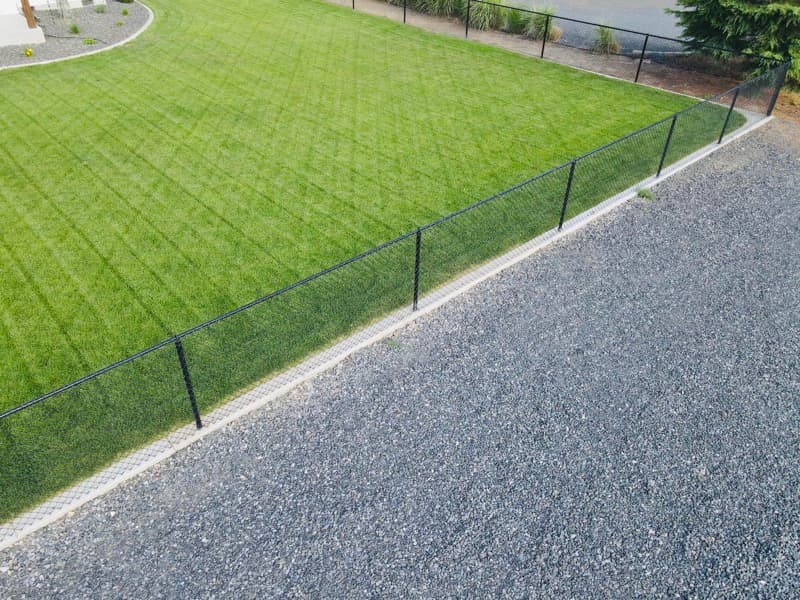 Black chain-link fence along a freshly mowed lawn