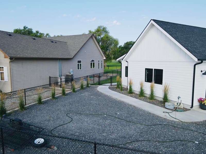 Gravel side yard with ornamental grasses and a black fence